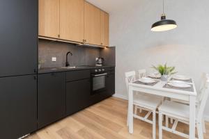 cocina con mesa blanca y nevera negra en Apartamenty Letnicka by Renters, en Gdansk