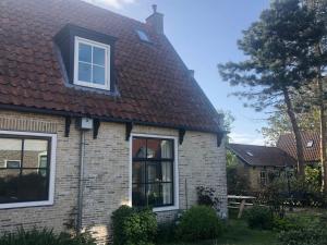 une maison avec un toit carrelé et une fenêtre dans l'établissement Herenweg Apartments, à Hollum