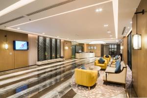 a hotel lobby with yellow chairs and a television at Aber Al Munsiyah in Riyadh