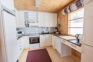 uma pequena cozinha com armários brancos e uma janela em Villa Aurora em Äkäslompolo
