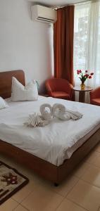 ein Bett mit weißer Bettwäsche auf einem Zimmer in der Unterkunft Hotel Prahova in Saturn