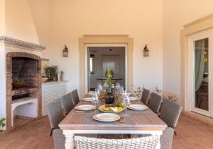 a wooden table with chairs and a plate of food on it at Villa Atlantic Blue Luxury with Ocean views in Ferragudo
