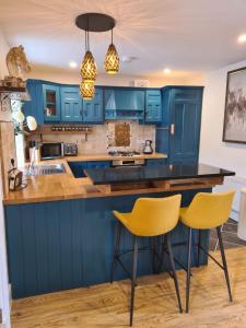 una cucina con armadi blu e sedie gialle di Dromod Lodge a Dromod