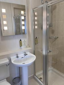 a white bathroom with a sink and a shower at Uplawmoor in Uplawmoor