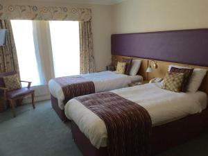 um quarto de hotel com duas camas e uma cadeira em Uplawmoor em Uplawmoor