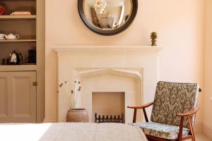 a bedroom with a fireplace and a chair and a mirror at The Yard in Bath Hotel in Bath
