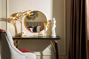 a table with a mirror and a lamp and a chair at Qult - The Aristocrat in Bucharest
