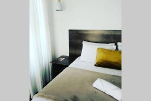 a bedroom with a bed with a yellow pillow at Olive Exclusive in Gaborone
