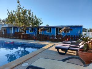 a pool with lounge chairs next to a blue house at Quinta do Sol in Lagos