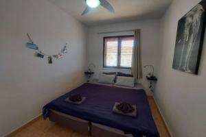 una camera da letto con un letto con lenzuola viola e una finestra di Arimar Seaview Puerto Rico a Puerto Rico de Gran Canaria