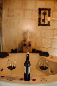 Prime Cappadocia Suites في نوشهر: زجاجة من النبيذ وكأسين على حوض الاستحمام