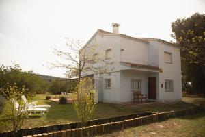 a white house with a table and a bench at MASIA BARTOMEU Rural house between vineyards 2km from the beach in El Vendrell