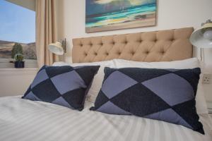 a bed with black and white pillows and a window at Raasay@Knock View Apartments, Sleat, Isle of Skye in Teangue