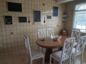 a dining room with a wooden table and white chairs at Piso Costa da Morte in Ponte Do Porto