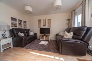 a living room with two leather couches and a television at Raasay@Knock View Apartments, Sleat, Isle of Skye in Teangue