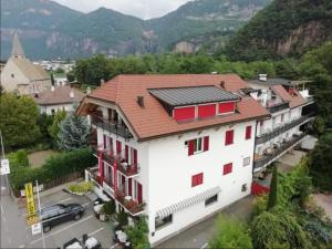 a white building with red windows and mountains in the background at Pension Flora in Auer