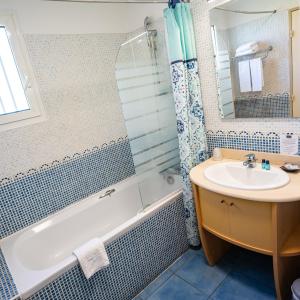 uma casa de banho com uma banheira, um lavatório e um chuveiro em Le Kerveguen em Saint-Gilles-les-Bains