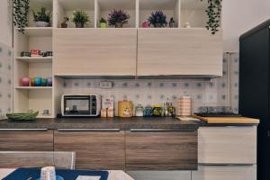 a kitchen with wooden cabinets and a microwave at Asariel Splendido appartamento vista mare e centro storico in Brindisi