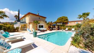 a swimming pool with chairs and a house at La Parenthèse de Villepey in Saint-Aygulf