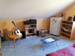 a living room with a guitar and a refrigerator at Chambre de l'Orée du Bois in Audeux