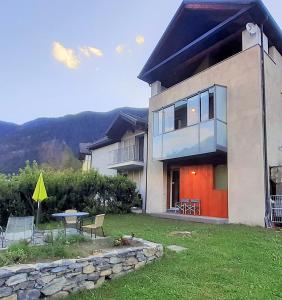 a house with a table and chairs in a yard at Maison 4 jardin - Casa design ai margini del bosco in Crodo