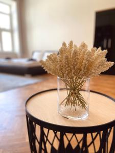 a glass vase with flowers sitting on a table at Luxury Vincents Apartments Kosice in Košice