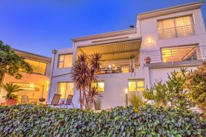 a large white building with chairs in front of it at Morgen Guesthouse Somerset West in Somerset West