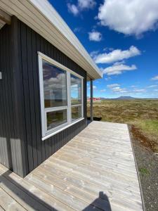 una terraza de madera junto a un edificio con ventana en Blue View Cabin 3B With private hot tub, en Reykholt