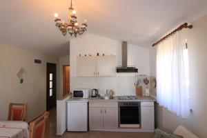 a small kitchen with white appliances and a chandelier at Apartments Gladiola Nin in Nin