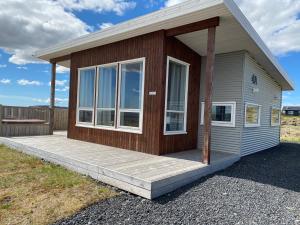 a small house with a wooden deck in a field at Blue View Cabin 4A With private hot tub in Reykholt
