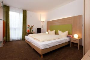 a bedroom with a large bed with a green headboard at Hotel Aviva in Karlsruhe