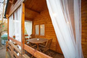 porche de una cabaña de madera con mesa de madera y sillas en Bungalow Tossa Pelada i Mobil Home Rodell en Fornols