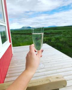 a person holding a wine glass on a porch at Blue View Cabin 1B With private hot tub in Reykholt