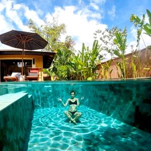 Eine Frau, die im Pool im Wasser sitzt. in der Unterkunft Alanta Pool Villa in Ko Lanta