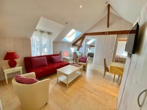 a living room with a red couch and chairs at Tilleul Plaza Résidence in Gérardmer