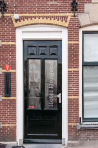 una puerta negra con un cartel en un edificio de ladrillo en Stadslogement Hoogend, en Sneek