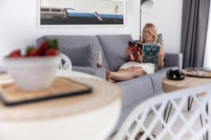 a woman sitting on a couch reading a book at Island Home Fuerteventura in Corralejo