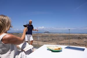 a woman taking a picture of a man with a glass of wine at Island Home Fuerteventura in Corralejo