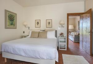 a bedroom with a large white bed and a living room at Borgo Iesolana in Bucine