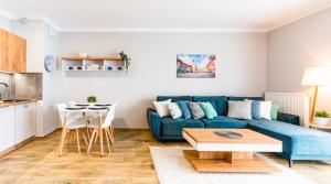 a living room with a blue couch and a table at Apartamenty Homely Place 2 - Parking in Poznań