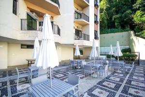 a patio with tables and white umbrellas and chairs at Real Residence Hotel in Rio de Janeiro