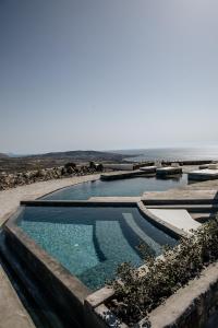 two swimming pools with the ocean in the background at Akrorama private villas and suites in Akrotiri