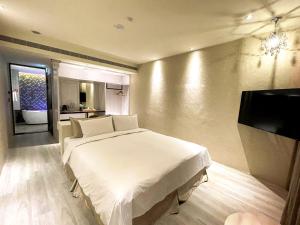a bedroom with a white bed and a flat screen tv at Fifth Avenue Motel in Taichung