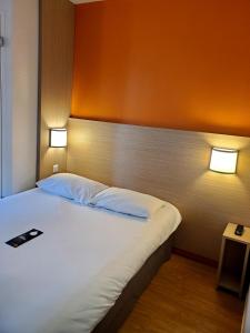 PREMIERE CLASSE ANGERS SUD Louvre Hotels group في ليه-بونت-دي-سي: غرفة نوم بها سرير وعليها مصباحين