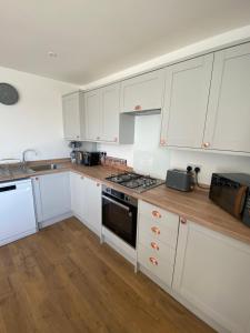 a kitchen with white cabinets and a stove top oven at Beau - Brambles Chine, Colwell Bay - 5 star WiFi - Short walk to The Hut and beach - 1 night stays available - Ferry offers in Freshwater