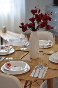 uma mesa com um vaso com flores vermelhas em Black Gate - 2 Bedroom Apartment in the Heart of Old Town with Free Private Secured Parking em Brasov