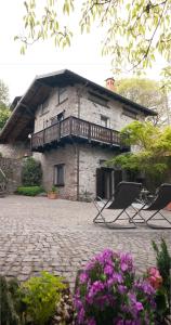 un bâtiment en pierre avec deux chaises et un balcon dans l'établissement Casa Vacanza Scacco d' Argento, à Darfo Boario Terme