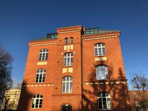 a tall red brick building with white windows at Dom & House - Apartments Waterlane Vintage in Gdańsk
