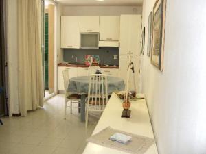 a living room with a table and a kitchen at Punta Ala Flat in Punta Ala