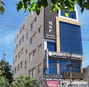 un edificio alto con señales delante en MSP Grands Inn, en Madurai